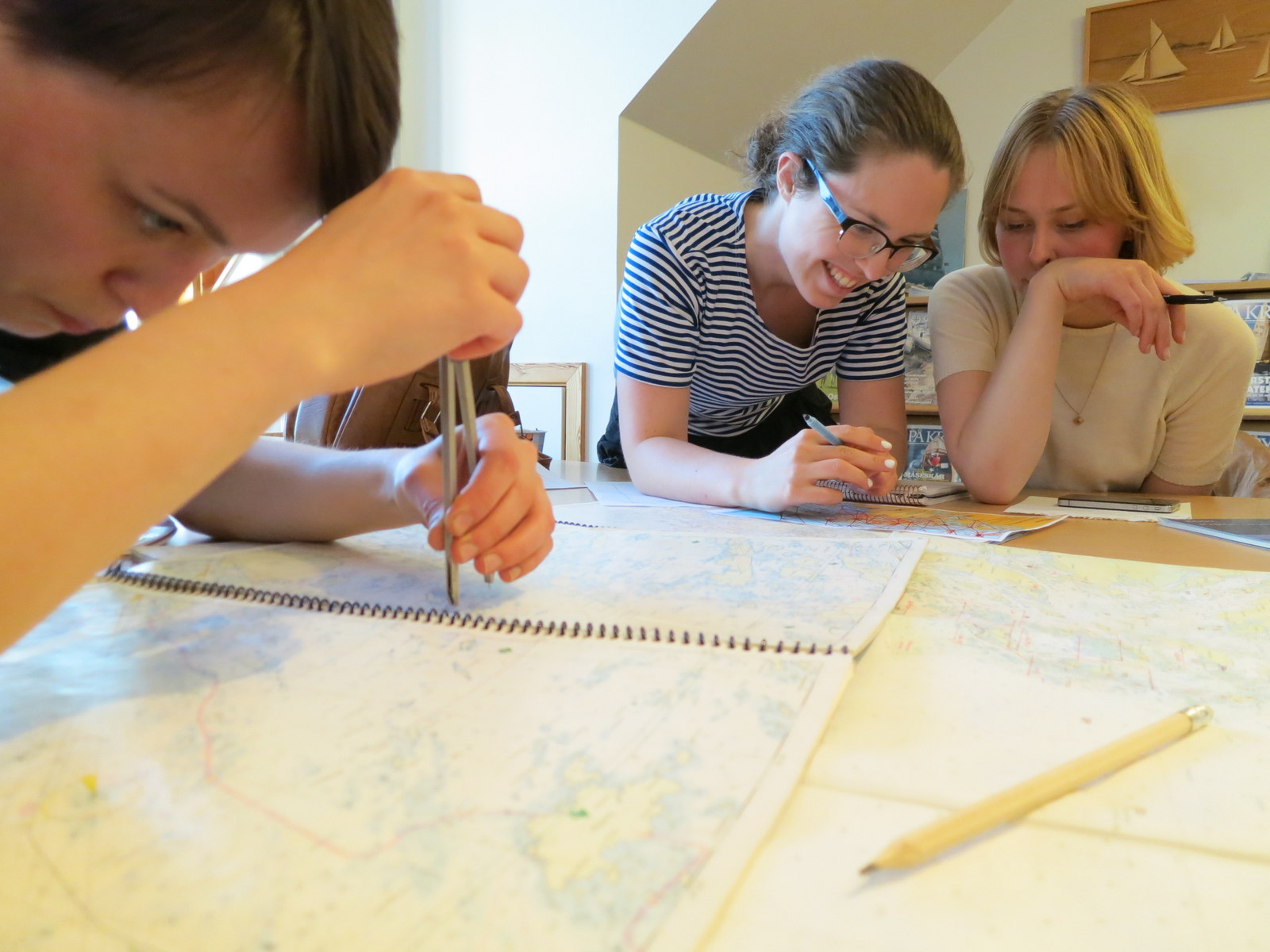 Foto på tre kvinnor som studerar ett sjökort ingående under en torrsegling.